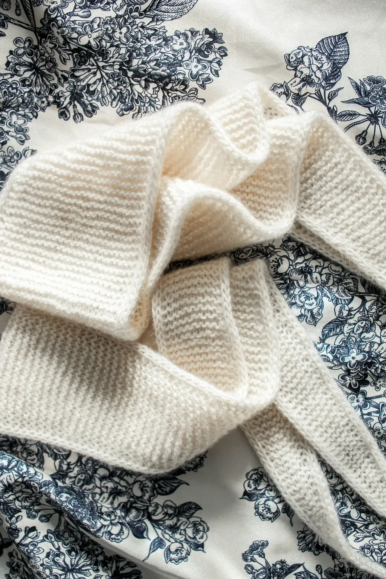 White knitted sweater laid on blue floral toile fabric